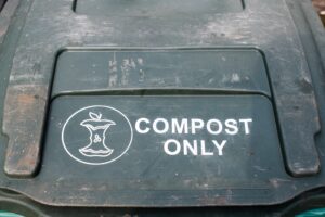 Green lid for compost collection cart that has an image of an apple core and says "COMPOST ONLY" in white letters.