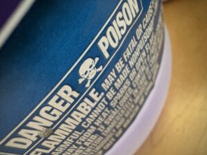 Warning label on a bottle that says "DANGER POISON" with a skull between the two works.