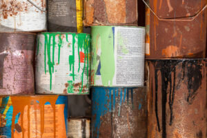 Stacks of metal paint cans with different colors of dripped paint on them.