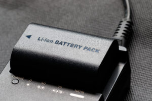 Rechargeable Lithium Ion Battery for Electronic Device being charged on a plug-in charger.