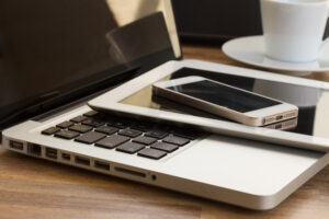 Laptop, tablet, and cell phone stacked in a pile
