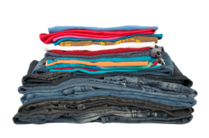 Pile of folded textiles - colorful shirts on top and jeans on the bottom.